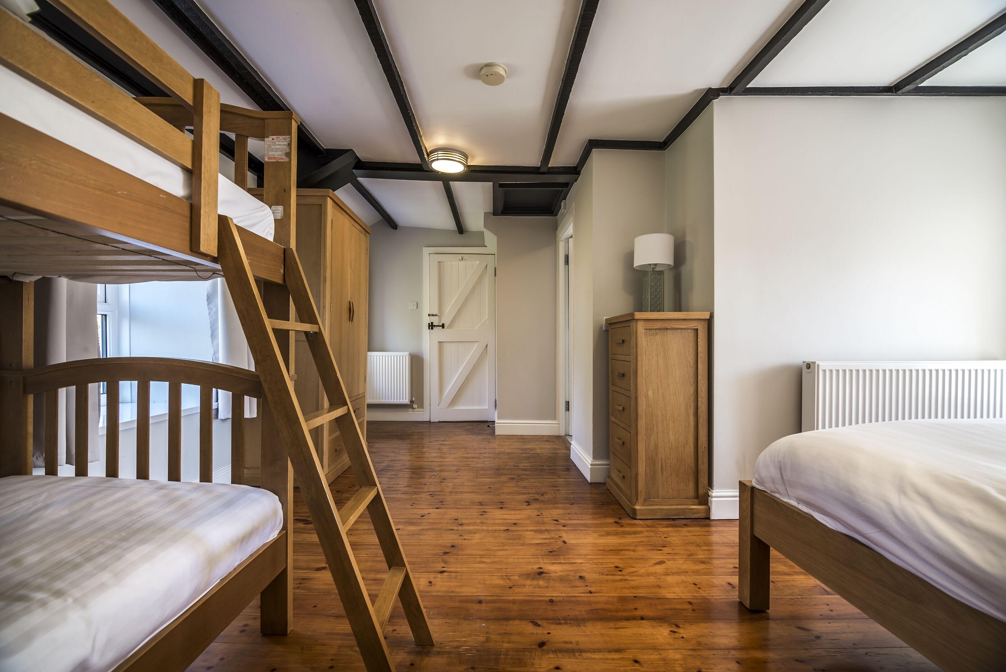 Quarto com beliche, escada de madeira, guarda-roupa e radiador.