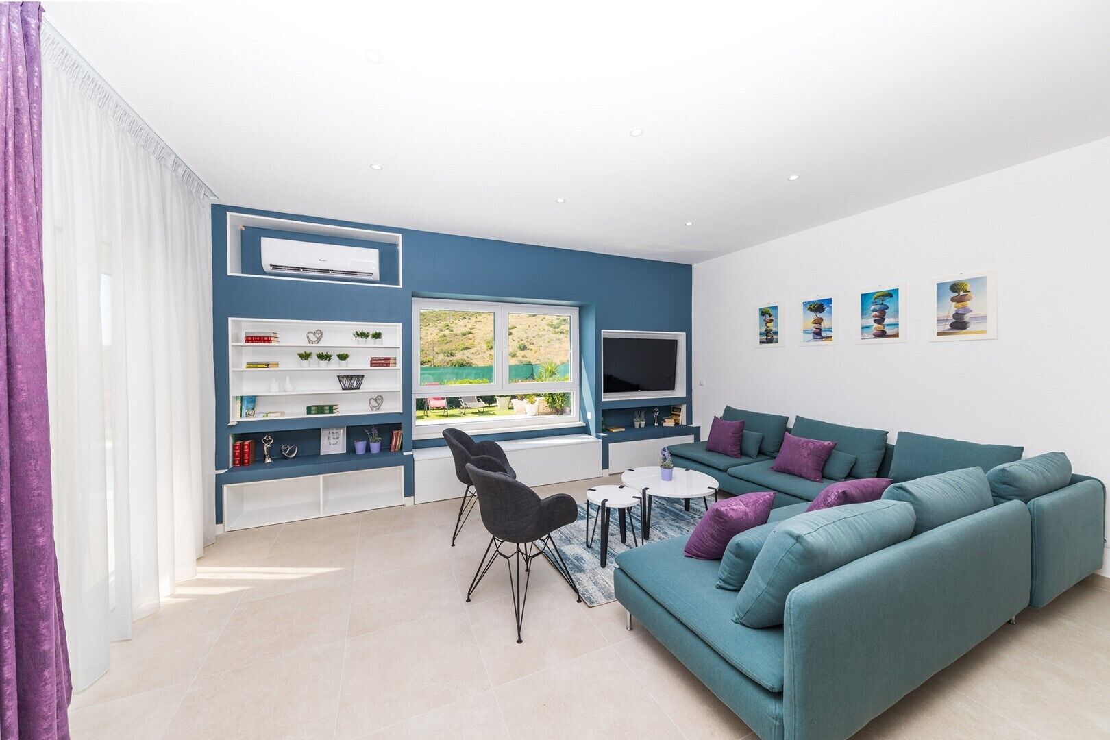 A modern living room with a blue sofa, a white coffee table, and a bookshelf.