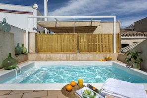 Relax by the serene pool surrounded by a fence, comfortable seating, and lush greenery.