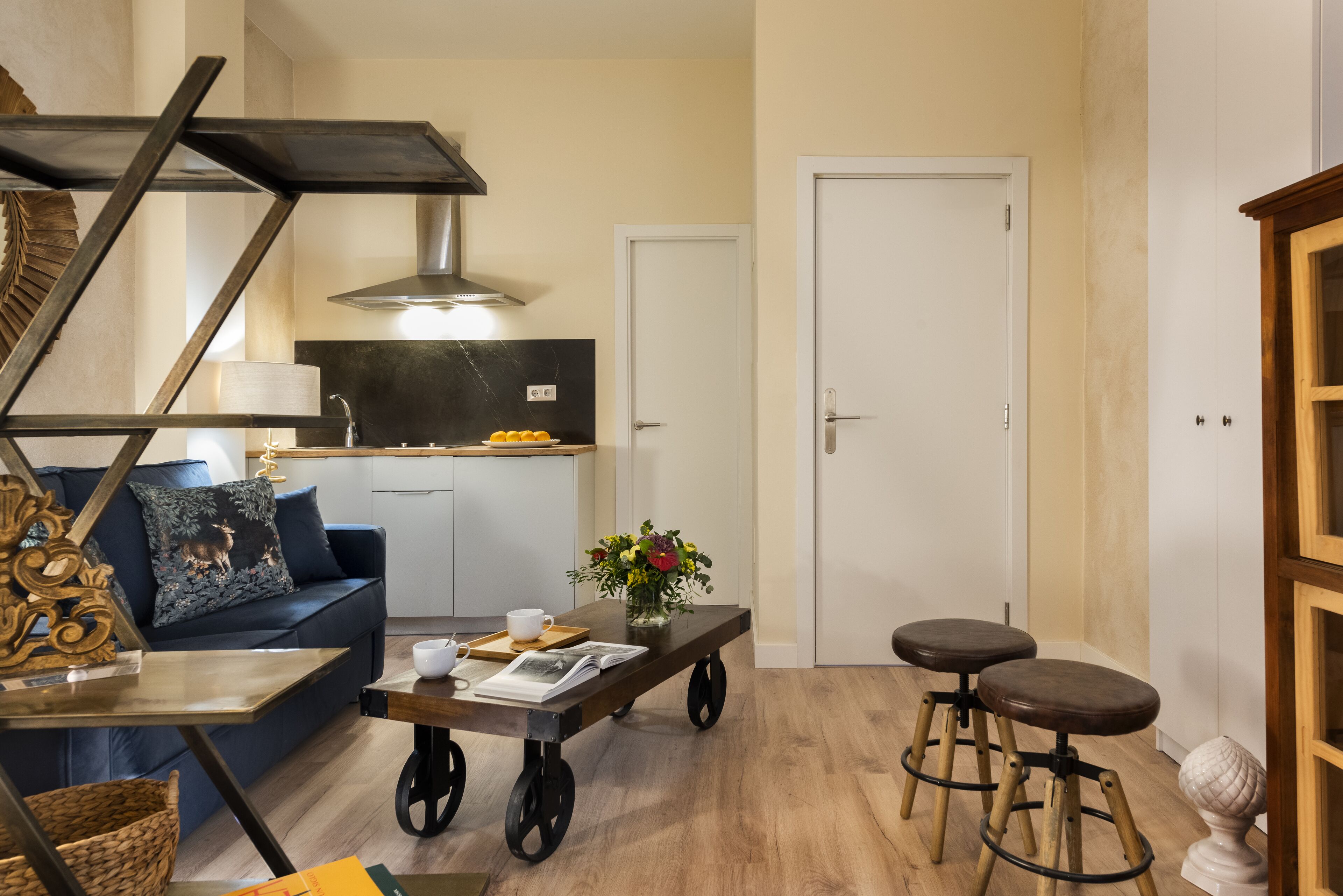 Ett kompakt bostadsutrymme med en soffa, ett soffbord, en köksdel och en dörr.