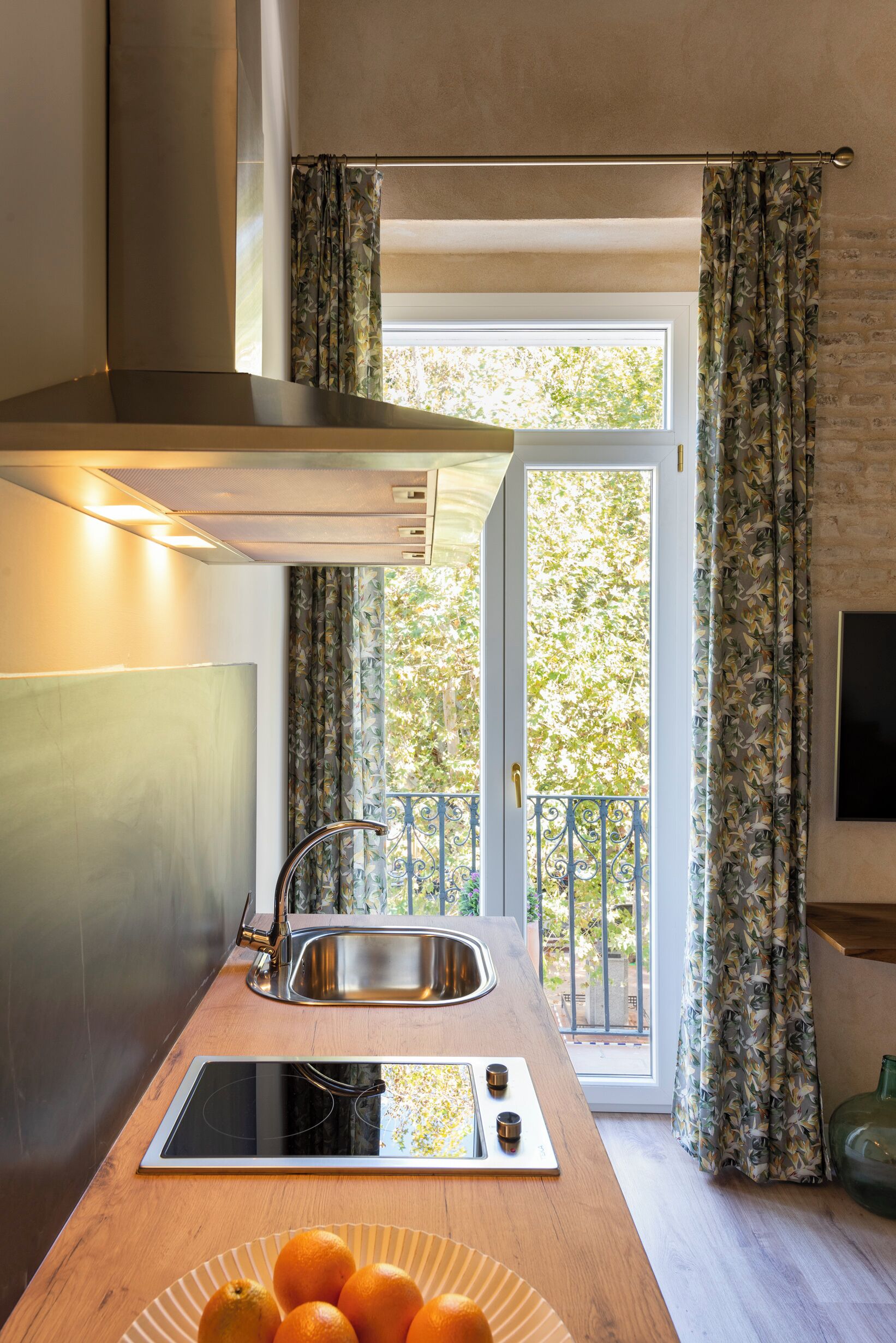 Une cuisine moderne équipée d’une cuisinière intégrée, d’un évier et d’une fenêtre avec des rideaux.