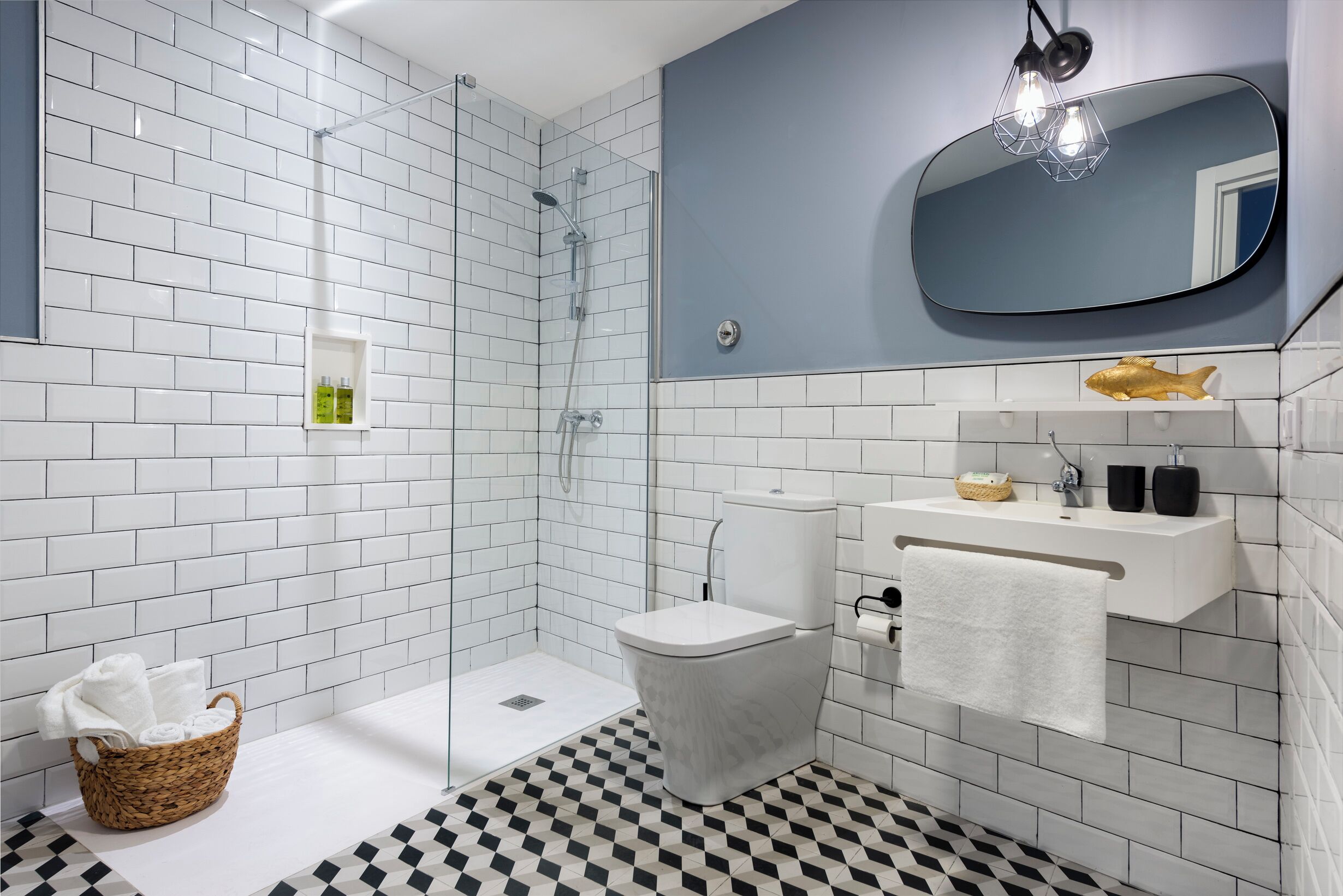 Een moderne badkamer met witte metro tegels, een zwart-wit geruite vloer, een wit toilet, een witte wastafel met handdoek, en een douche met glazen deur.