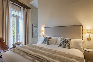 Relax in a classic room with a large bed, wooden headboard, and leather armchair.