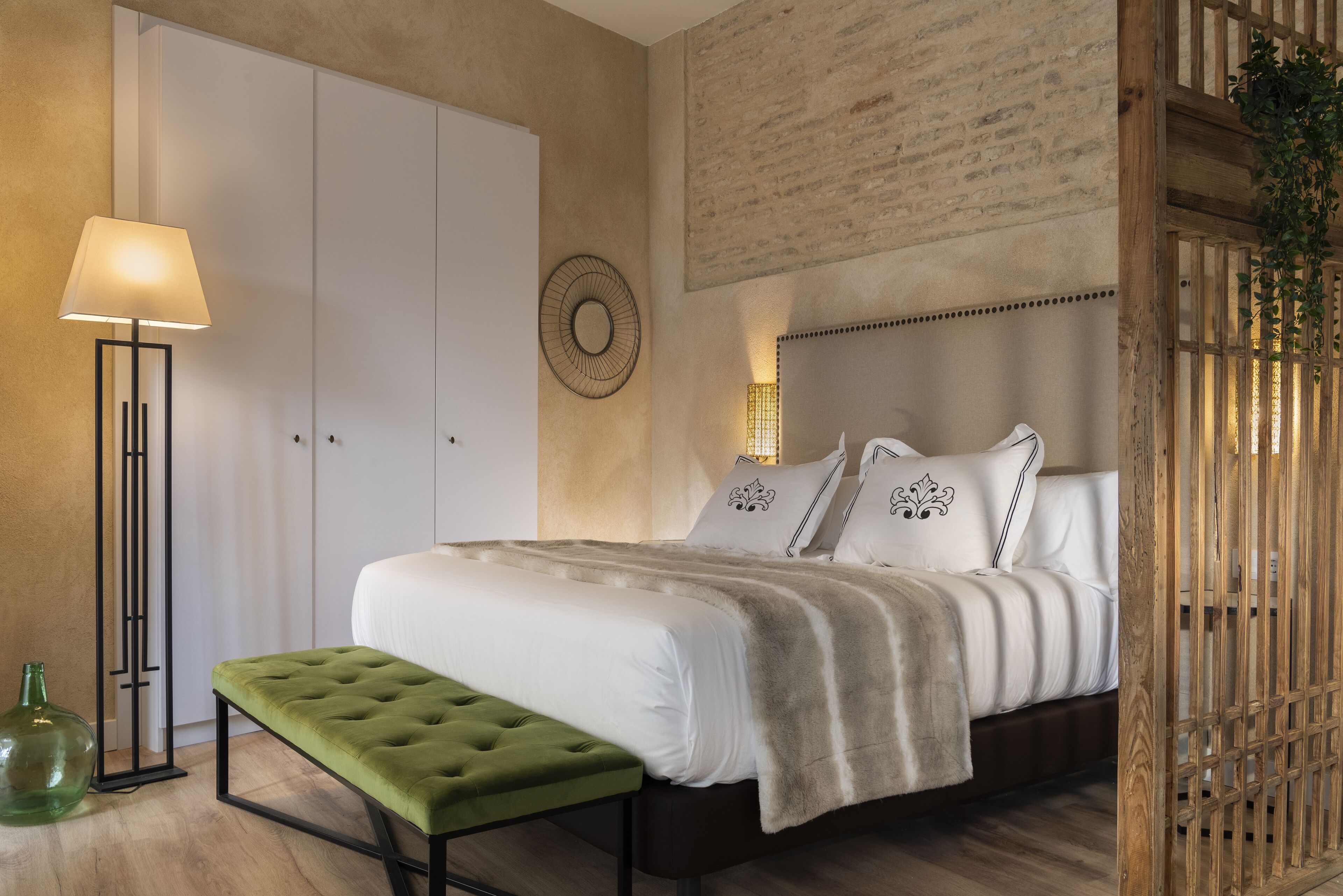A bedroom with a bed, a bench, a floor lamp, and a wardrobe.