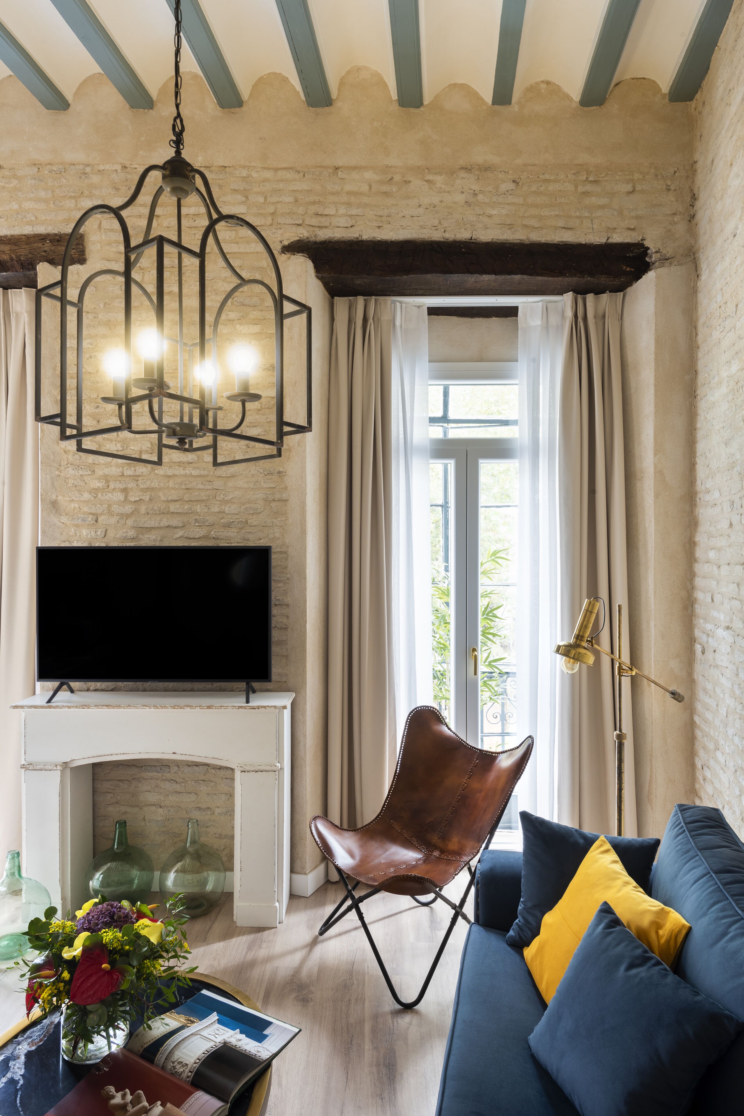 A living room with a fireplace, a television, a sofa, a chair, and a chandelier.