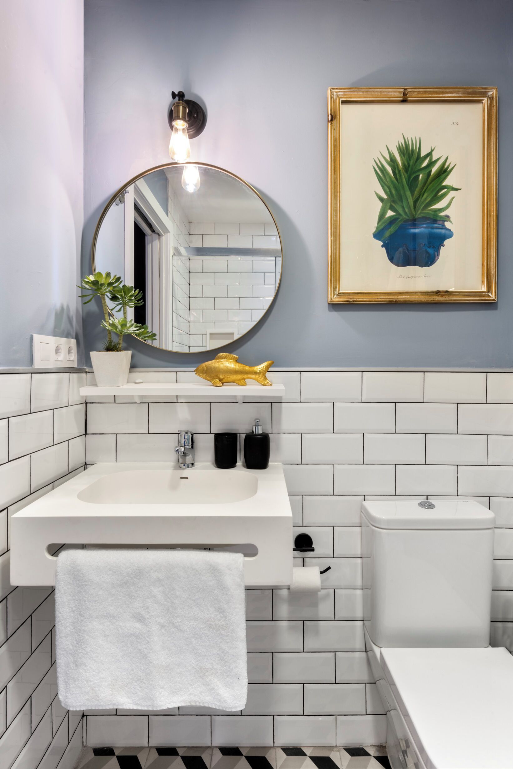 A bathroom with a white sink, a mirror, a toilet, and a framed plant on the wall.