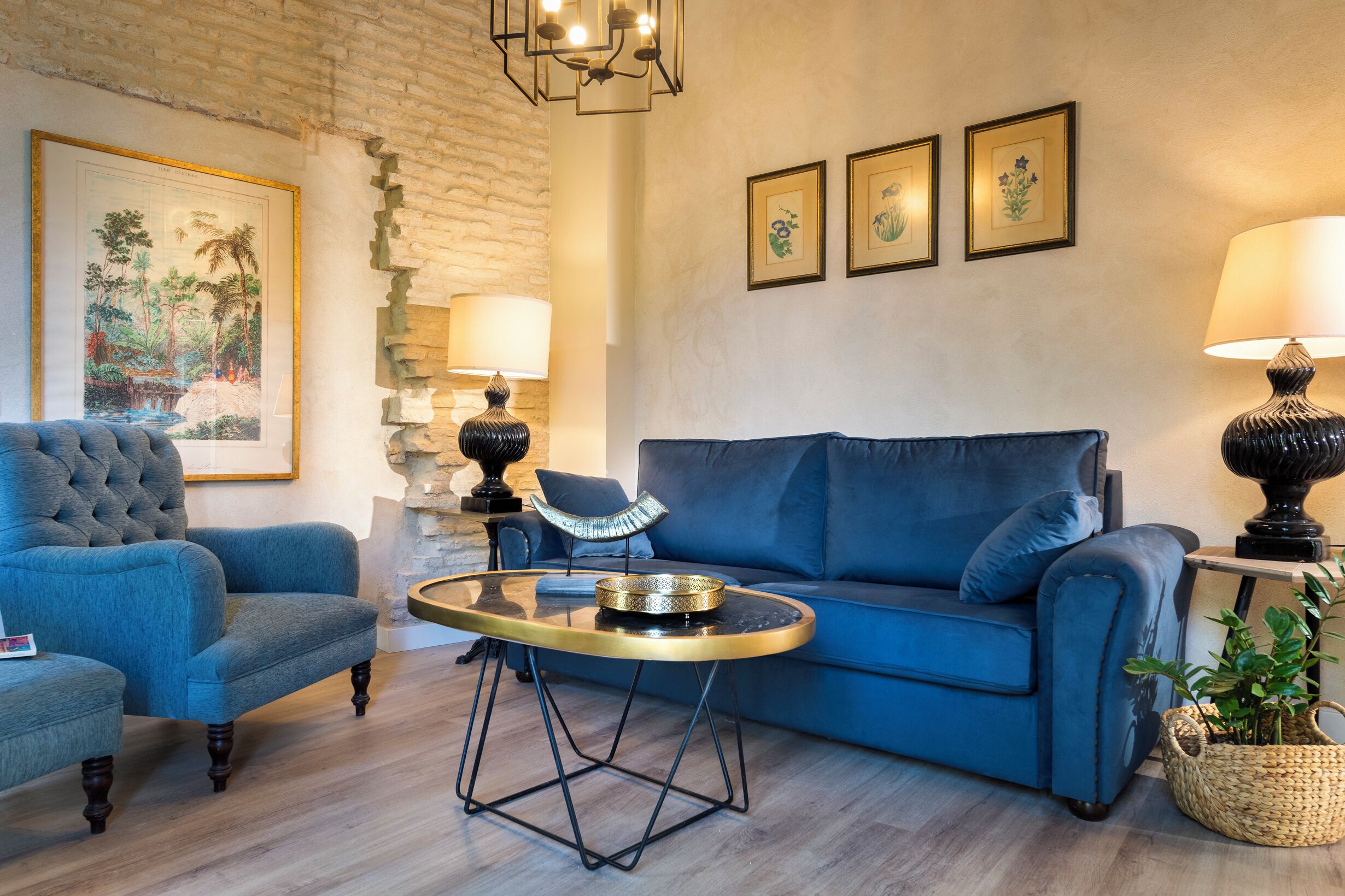 A living room with a blue sofa, a blue armchair, a glass coffee table, and a lamp.