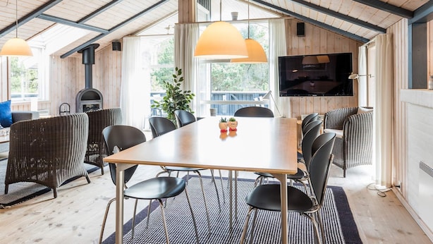 Un accogliente soggiorno open space con soffitto in legno, un tavolo grande e posti a sedere comodi.