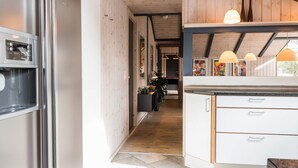Una cucina moderna con frigorifero in acciaio inossidabile, mobili bianchi e soffitto in legno.