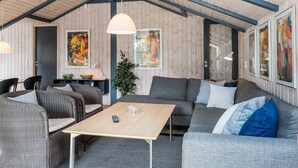 Un interno accogliente con soffitto alto, pareti in legno, un divano, un tavolo da pranzo e opere d'arte alle pareti.