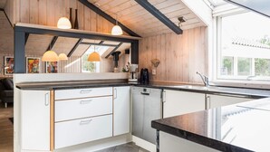 Una cucina moderna con mobili bianchi, un piano di lavoro nero e illuminazione a sospensione.