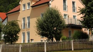 A two-story building with a red-tiled roof, a balcony, and a wooden fence in front. - Pension & Ferienwohnung Breitmoser (Riedenburg)
