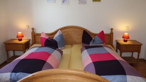 A double bed with a wooden headboard, two bedside tables with lamps, and a colorful quilt. - Pension & Ferienwohnung Breitmoser (Riedenburg)