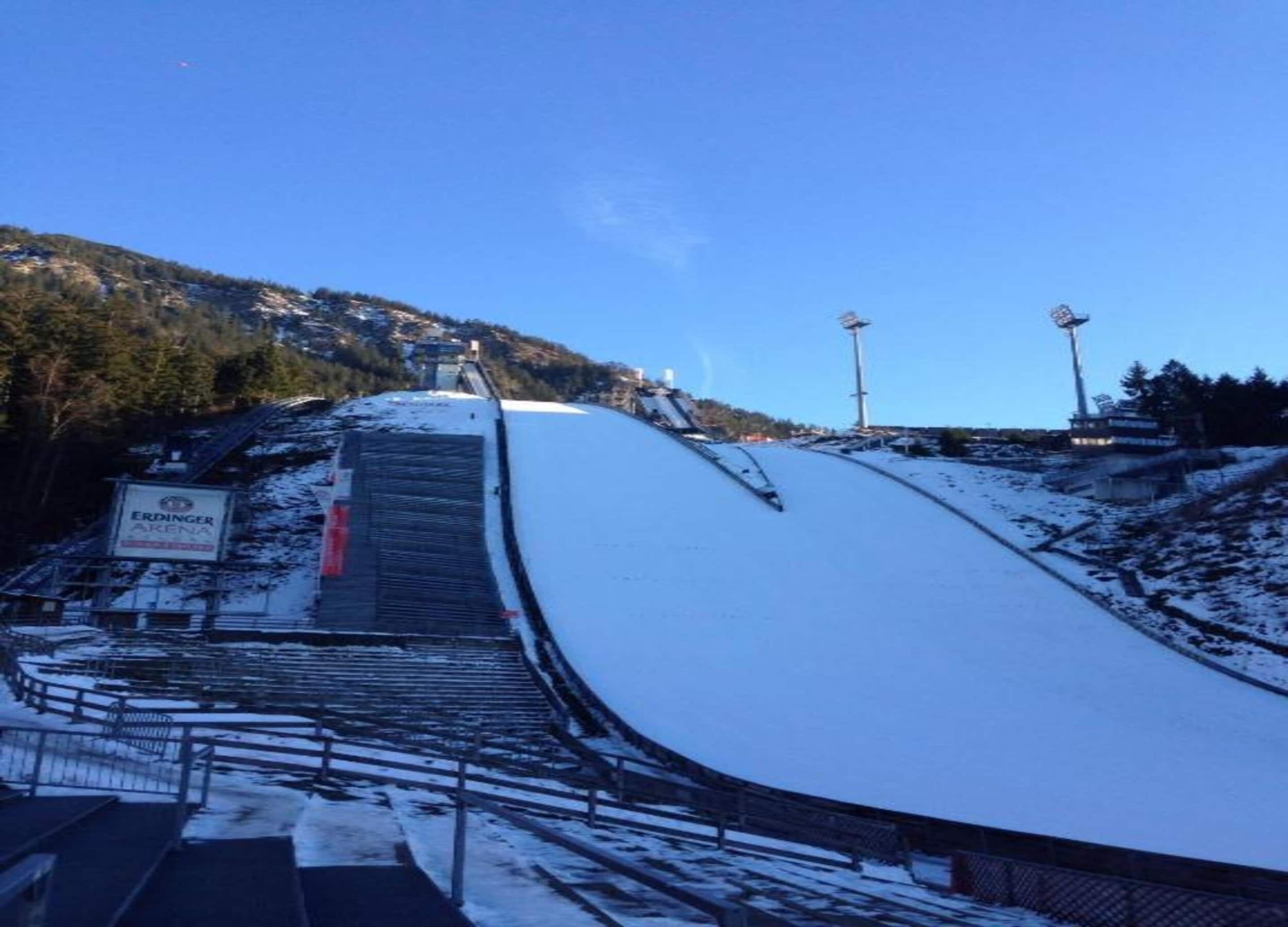 A snow-covered ski slope with a sign for 'Erding Arena' and a chairlift.