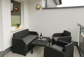 A balcony with a sofa, two chairs, a small table, a bottle of wine, and two wine glasses. - Wohnung mit Balkon und Toller Aussicht (Willingen)