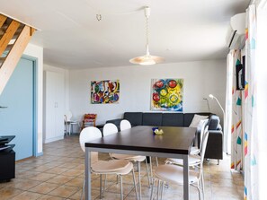 A dining area with a table, chairs, and a hanging light fixture. - 6 Person Holiday Home in Hvide Sande (Hvide Sande)