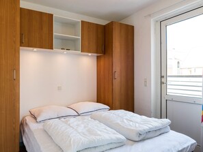 A bedroom with a bed, wooden wardrobe, and a window. - 6 Person Holiday Home in Hvide Sande (Hvide Sande)