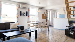 Ein modernes Wohnzimmer mit einer Couch, einem Esstisch mit Stühlen und einer TV-Konsole.