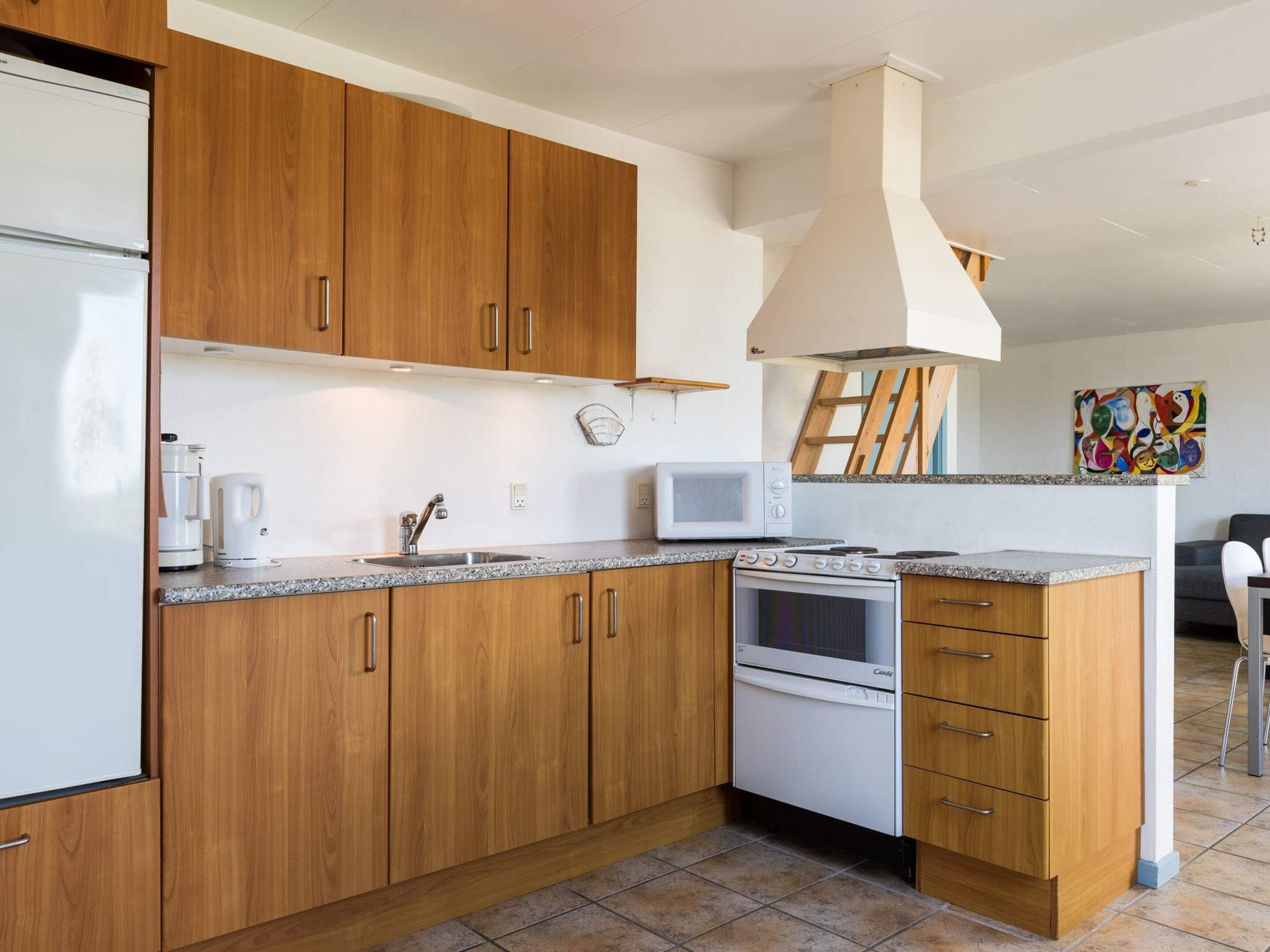 A modern kitchen with wooden cabinets, a built-in microwave, a stove, and a coffee maker.