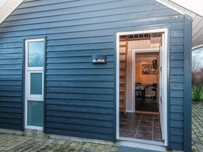 A blue building with a door leading to a room with a fireplace and a table. - 5 Star Holiday Home in Tarm (Tarm)