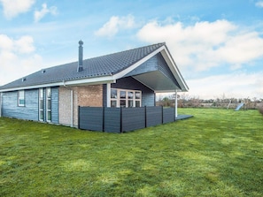 Ein modernes Haus mit geneigtem Dach, einem Backsteinbereich und einem umzäunten Garten.