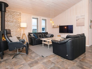 Ein modernes Wohnzimmer mit Kamin, Ledersofas, einem Couchtisch und einem Flachbildfernseher.
