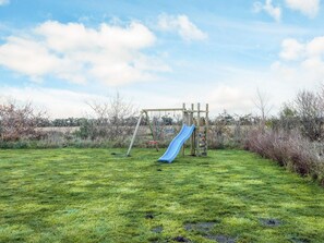 A playground with a slide and swings in a grassy field. - 5 Star Holiday Home in Tarm (Tarm)