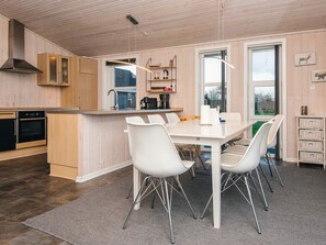 A modern kitchen with wooden cabinets, a central island, and white chairs. - 5 Star Holiday Home in Tarm (Tarm)