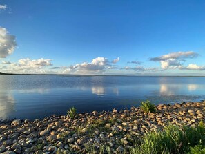 A calm lake with a rocky shoreline and a clear sky. - 4 Star Holiday Home in Henne (Henne)