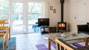 Ein gemütliches Wohnzimmer mit Kamin, Fernseher und Glastisch.