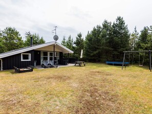 A cabin with a patio, a swing set, and a picnic table. - 4 Star Holiday Home in Henne (Henne)