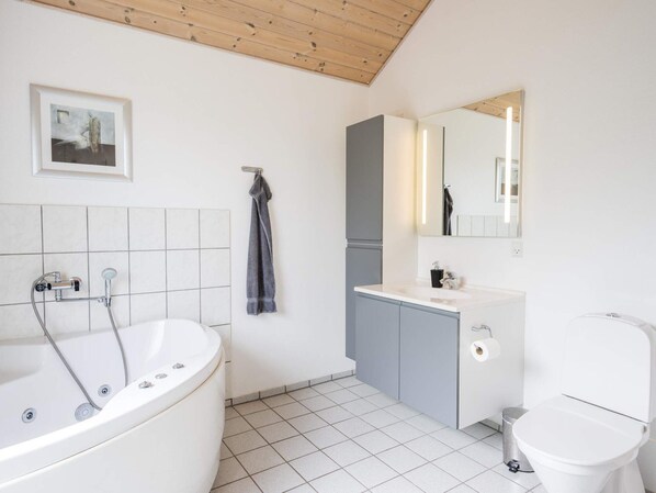 A modern bathroom with a freestanding bathtub, a toilet, a sink, and a mirror.