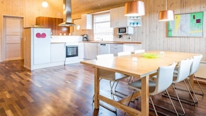 A modern kitchen with wooden flooring, white cabinetry, a central island, and pendant lighting. - 4 Star Holiday Home in Tarm (Tarm)