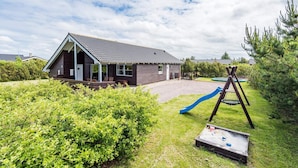 A house with a covered porch, a blue slide, and a swing set in a grassy yard. - 4 Star Holiday Home in Tarm (Tarm)