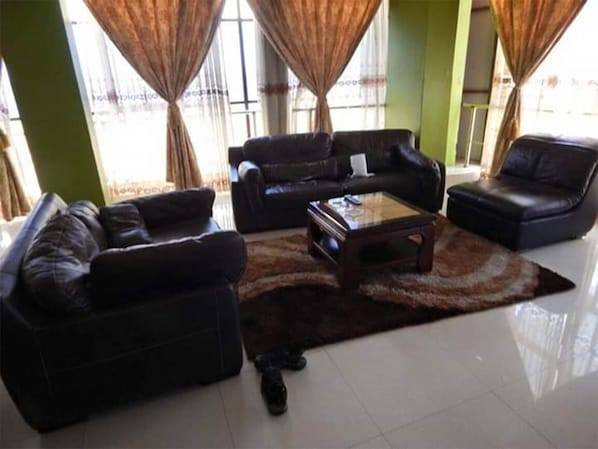 A living room with two black leather sofas, a coffee table, and a rug.