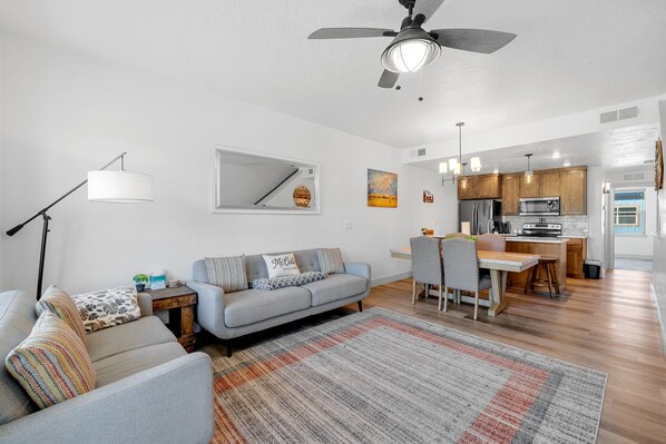 A modern living room with a sofa, a dining area, and a kitchen in the background. - The Highland Hangout: Luxurious, new 3 bed, 3 bath townhome in McCall with garage (McCall)
