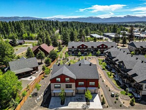 A residential area with modern houses, a paved road, and a forested background with mountains. - The Highland Hangout: Luxurious, new 3 bed, 3 bath townhome in McCall with garage (McCall)