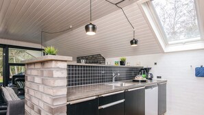 Une cuisine moderne dotée d’un îlot central intégré, de meubles de rangement noirs et d’un puits de lumière.