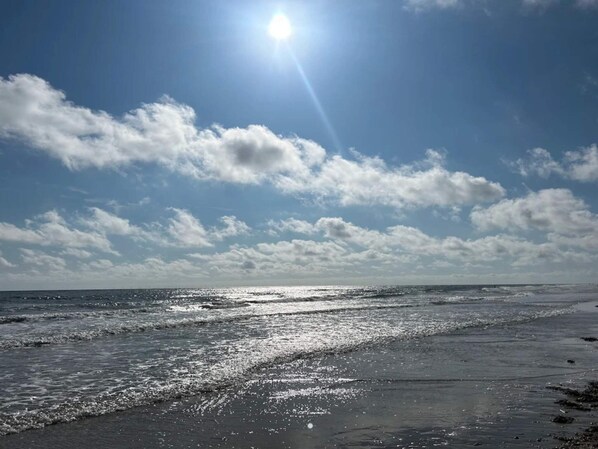 A beach with waves and a clear sky.
