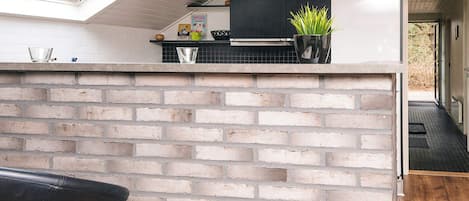A kitchen with a brick wall, a black countertop, and a skylight.