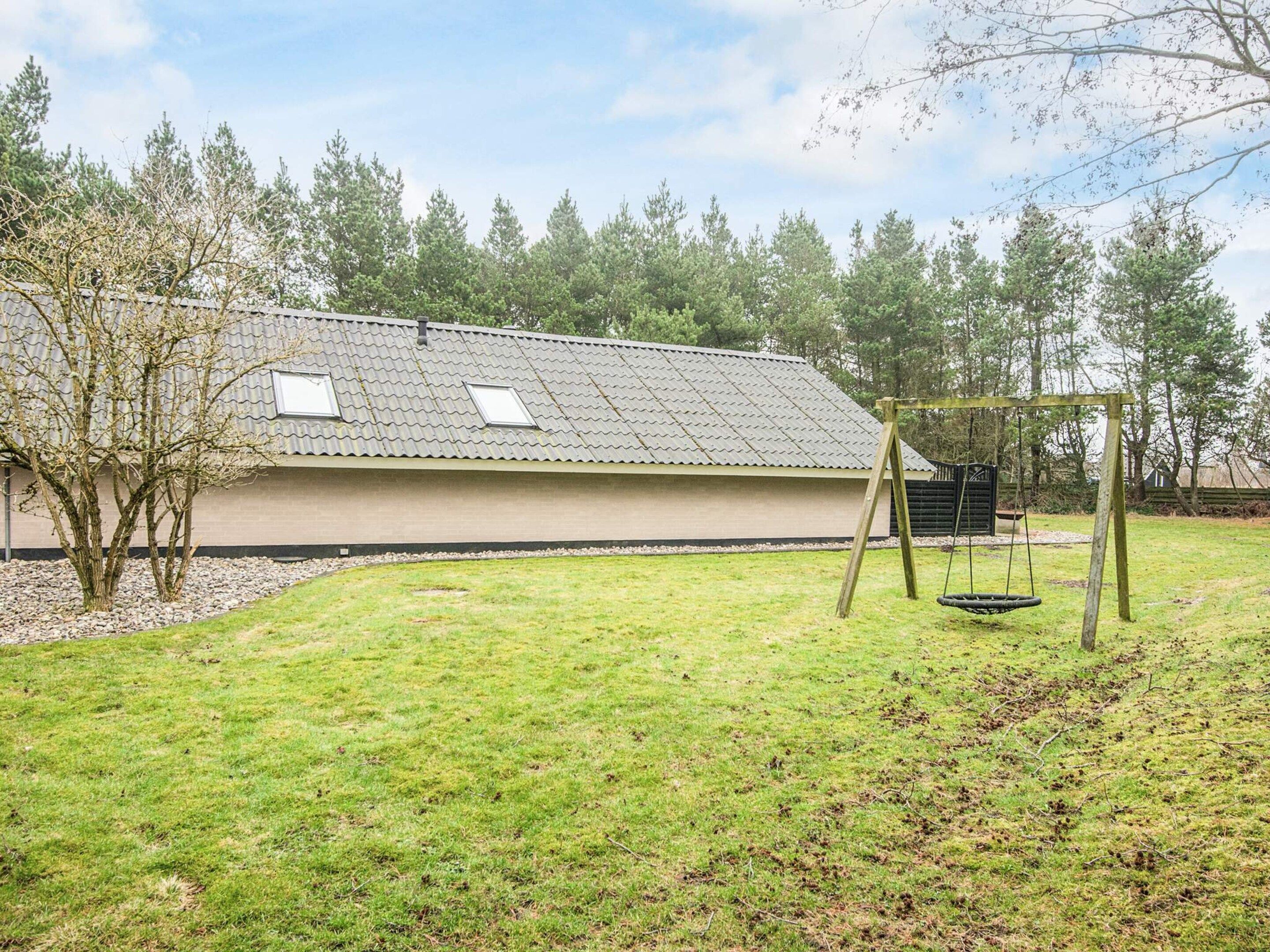 Un bâtiment doté d’un toit en pente, d’une balançoire et d’une cour gazonnée.