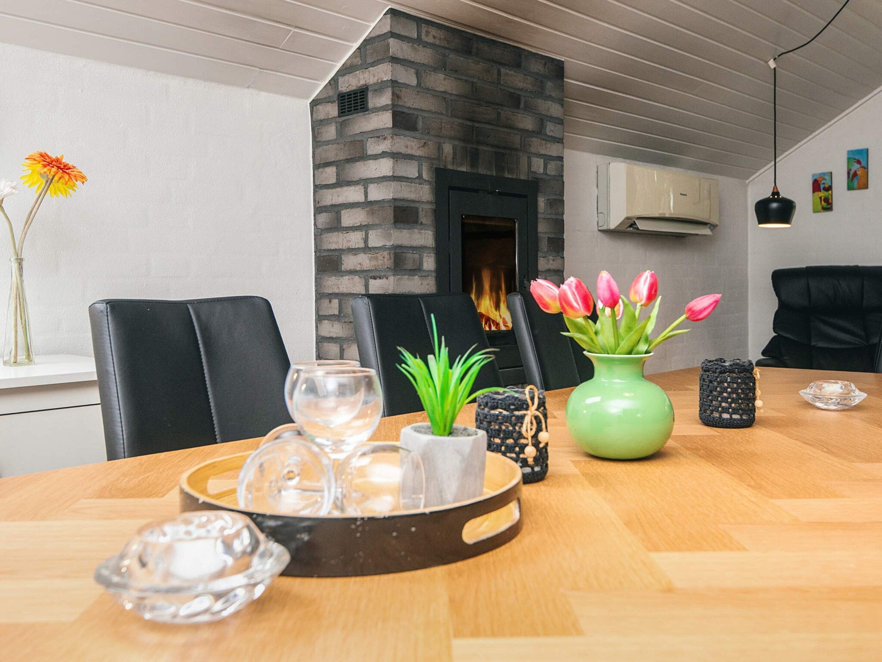 Ein Essbereich mit einem Holztisch, Stühlen, einer Blumenvase und einem Kamin.