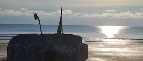 Una estructura de concreto con grafitis en una playa, con el océano al fondo.