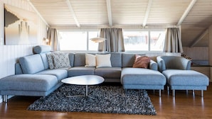 A modern living room with a sectional sofa, a round coffee table, and a patterned rug. - Bright Dune View Cottage-by Traum (Hvide Sande)