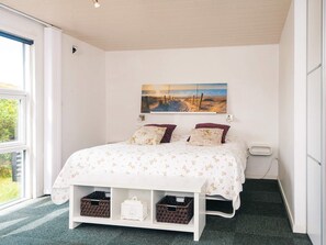 A bedroom with a bed, a painting, a window, and storage baskets. - 5 Star Holiday Home in Fano (Fano)