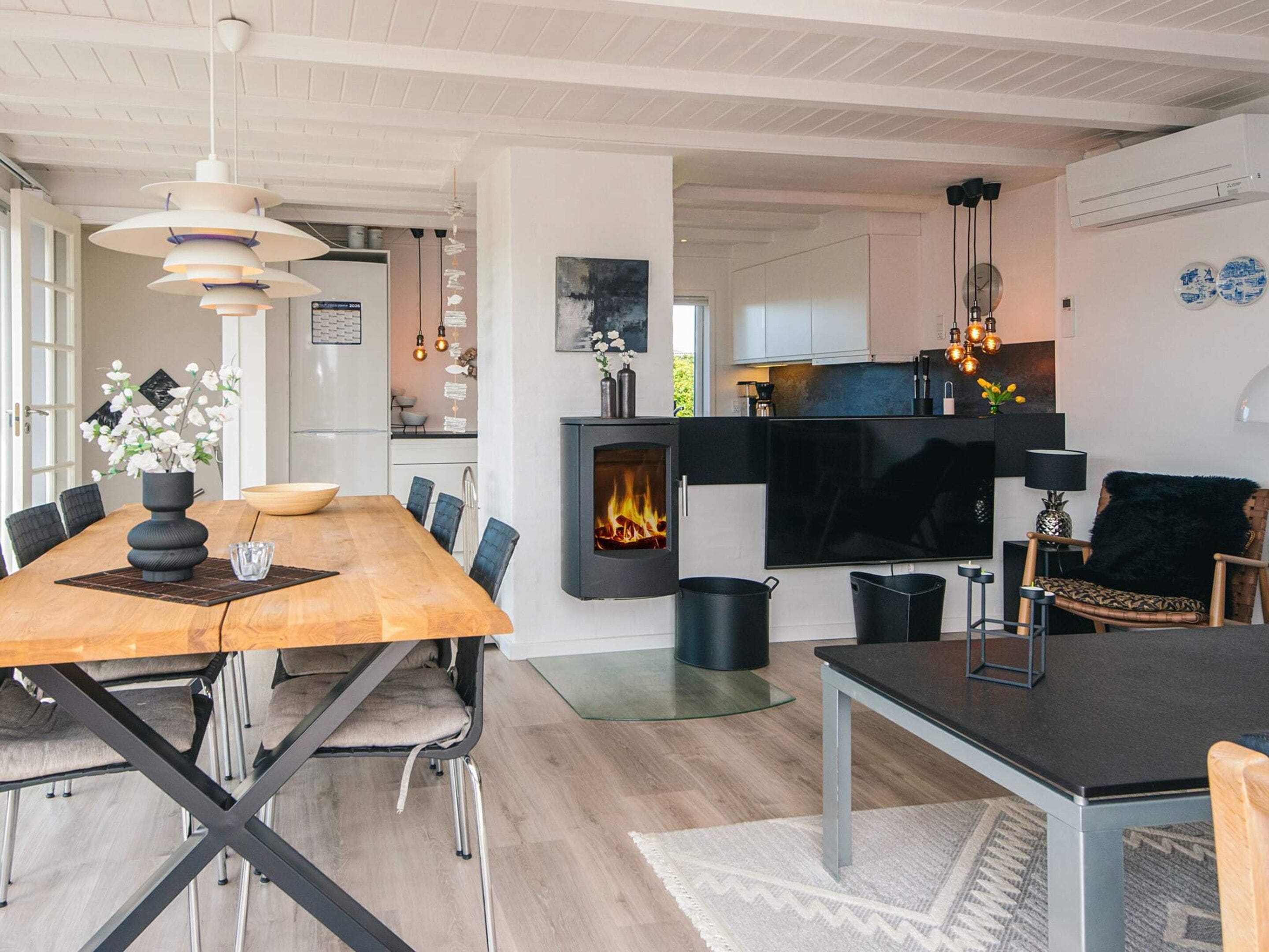 A modern living room with a fireplace, dining area, and kitchen.