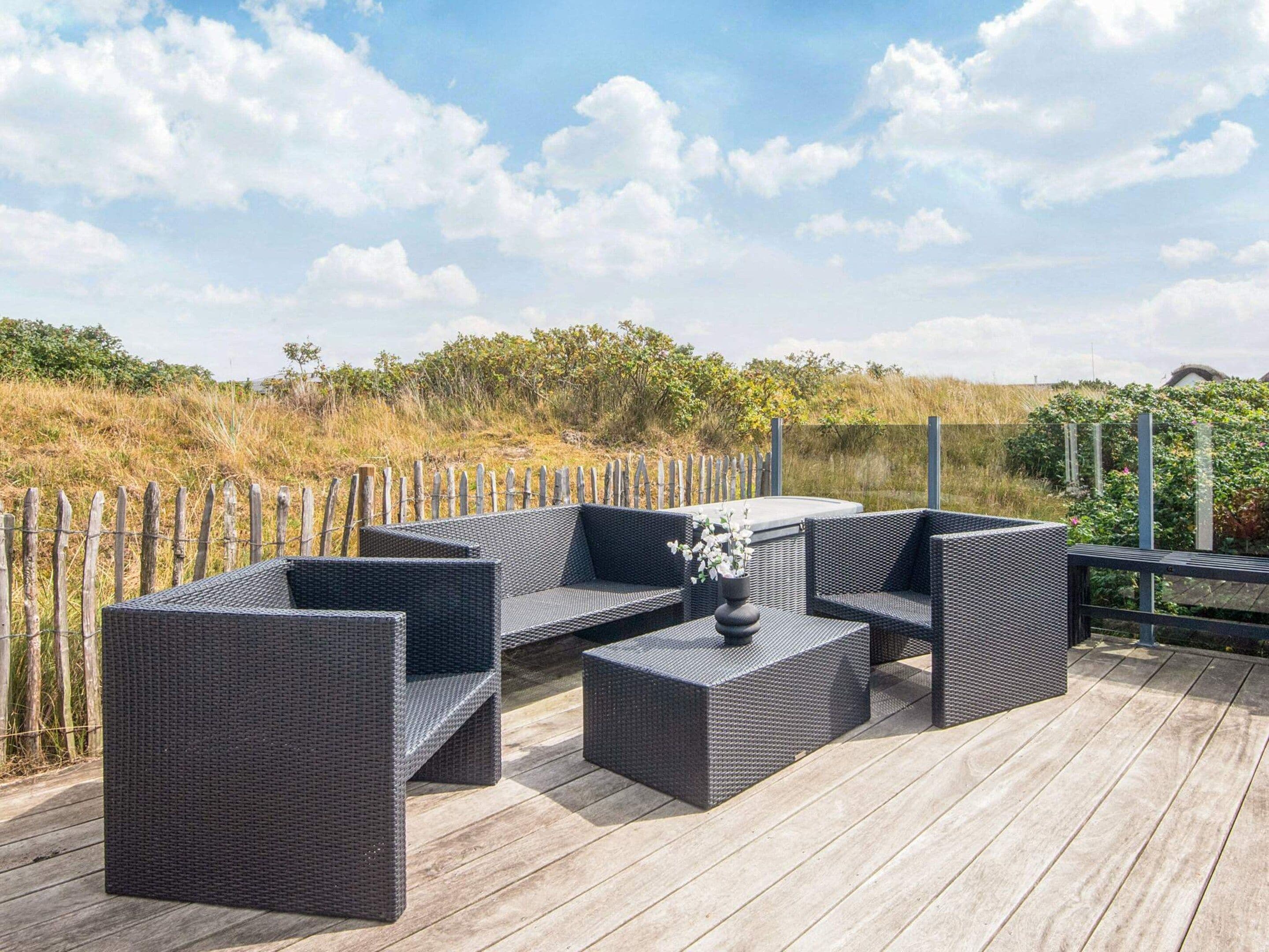 An outdoor seating area with wicker furniture and a hot tub on a wooden deck.