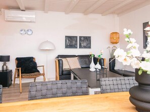 A modern living room with a sofa, chairs, a dining table, and a lamp. - 5 Star Holiday Home in Fano (Fano)