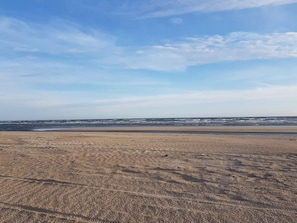 A beach with a wide sandy area and a calm sea under a clear sky.
