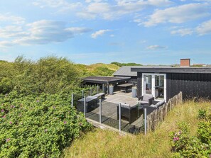A modern outdoor deck with seating and a glass door leading to a covered area. - 5 Star Holiday Home in Fano (Fano)